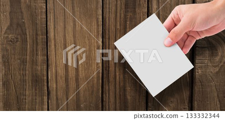 Hand holding paper against wooden wall Hand holding paper against wooden wall 133332344