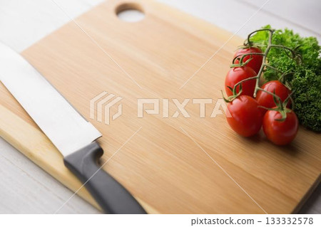 Tomatoes with parsley and knife on chopping board 133332578
