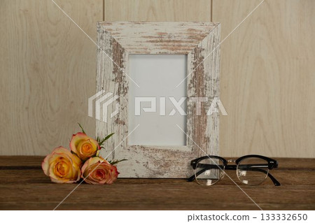 Photo frame, spectacle and flowers on table Photo frame, spectacle and flowers on table 133332650
