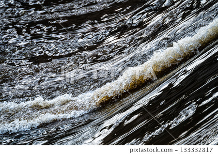close up of flowing water, rapid water splashes of an white water river or stream, bubbly water 133332817