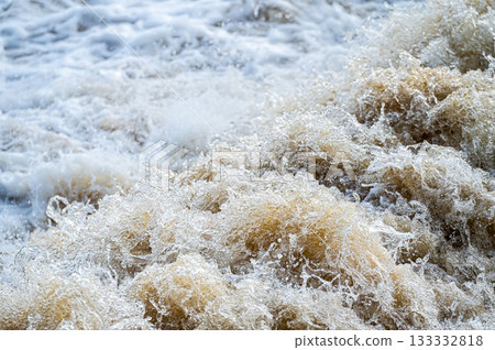 close up of flowing water, rapid water splashes of an white water river or stream, bubbly water 133332818