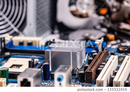 part of computer circuit board with components on the background of defocused power supply fans, close-up 133332859