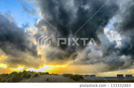 Clouds break as golden rays illuminate shoreline landscape 133332883