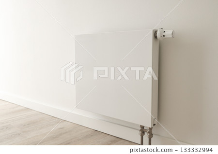 Sleek white radiator mounted on a wall in a minimalist room 133332994