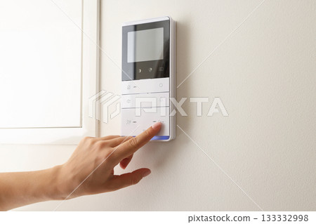 A person tweaks the temperature on a sleek panel 133332998
