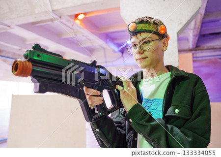Young player enjoys laser tag in an indoor arena Young player enjoys laser tag in an indoor arena 133334055
