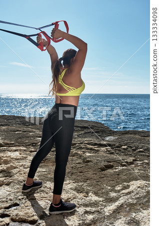 young woman exercising with hula hoop on beach 133334098