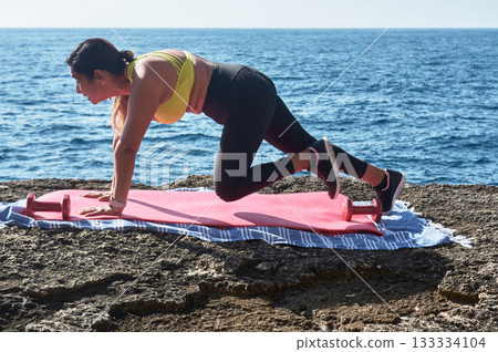 woman doing yoga exercises on beach 133334104