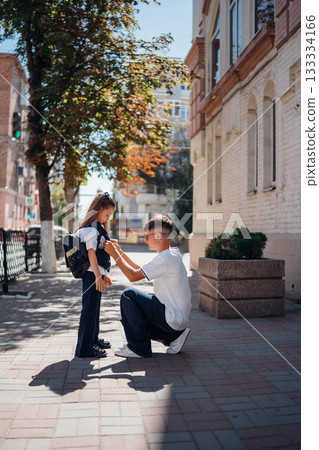 Father adjusts daughter backpack on a sunny day in the city 133334166