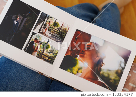 Female hands flipping through a photo book with wedding photos 133334177