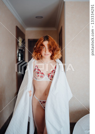Young woman wearing floral lingerie and a white towel in hotel hallway 133334291