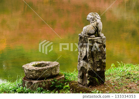 Komainu guardian dogs gazing at the pond reflecting autumn leaves 133334353