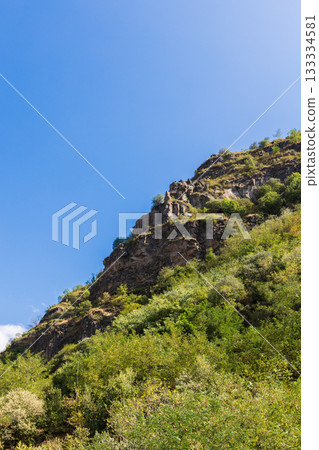 A vibrant mountain scene showing a steep hillside covered in green shrubs A vibrant mountain scene showing a steep hillside covered in green shrubs 133334581