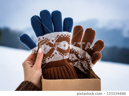 藍棕色手工編織的北歐風格五指手套,裸露的雙手置於模糊的雪景背景前。冬季禮物。 藍棕色手工編織的北歐風格五指手套,裸露的雙手置於模糊的雪景背景前。冬季禮物。 133334890