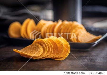 Crispy potato chips on wooden table. 133335863