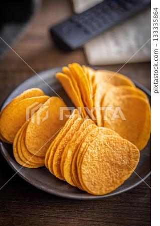 Crispy potato chips on plate on wooden table. Crispy potato chips on plate on wooden table. 133335864