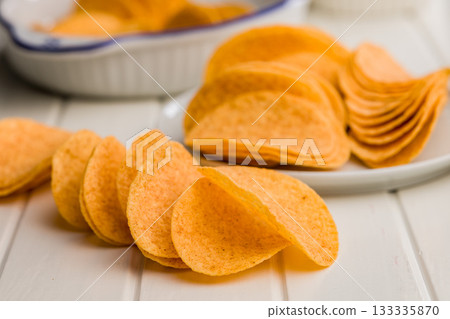 Crispy potato chips on white table. Crispy potato chips on white table. 133335870