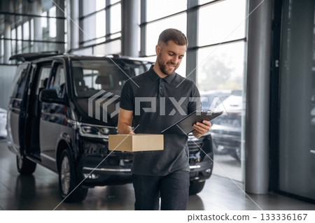 Fast delivery service, standing. Man loader is near the car with a box Fast delivery service, standing. Man loader is near the car with a box 133336167