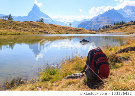 Tourist backpack on background of Leisee lake and Matterhorn mountain on the Five Lakes Trail in Zermatt, Switzerland 133336422
