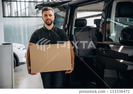 Big order, holding the box. Delivery man or loader is near the car with Big order, holding the box. Delivery man or loader is near the car with 133336472