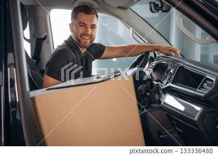 The delivery man or a loader is in the car with box 133336480