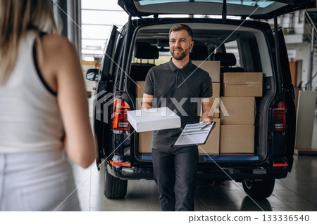 Customer is taking her order. Woman is with delivery man, with the car 133336540