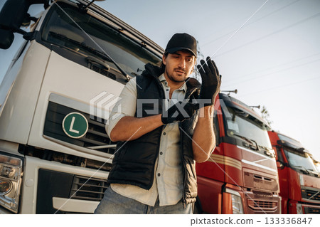 Getting ready for a work, wearing gloves. Truck driver is near the transport outdoors 133336847