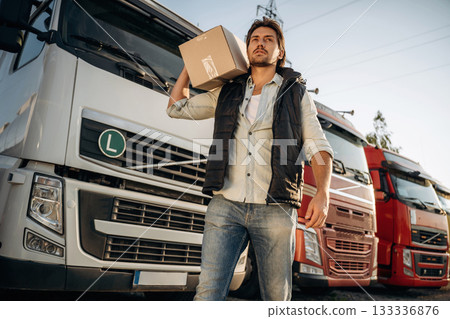 Delivery is on the way, with box. Truck driver is near the transport outdoors Delivery is on the way, with box. Truck driver is near the transport outdoors 133336876