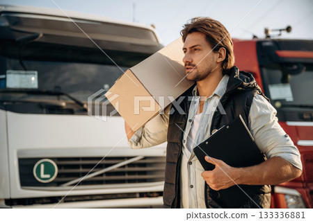 Shipping conception, with box. Truck driver is near the transport outdoors 133336881