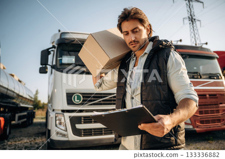 Shipping conception, with box. Truck driver is near the transport outdoors 133336882