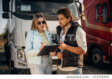 Truck driver is with woman, doing business, holding notepad, documents 133336895