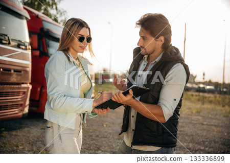 Truck driver is with woman, doing business, holding notepad, documents 133336899