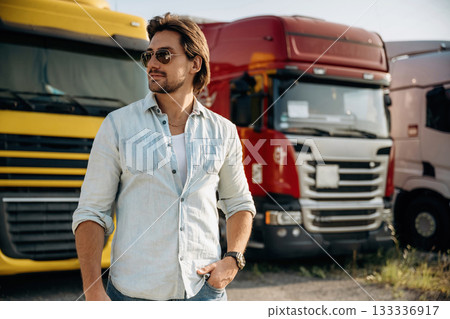 In sunglasses. Truck driver is near the transport outdoors In sunglasses. Truck driver is near the transport outdoors 133336917