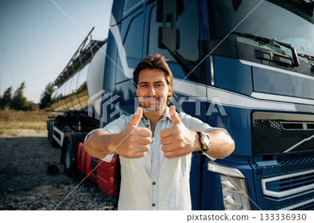 Thumbs up, standing. Truck driver is near the transport outdoors Thumbs up, standing. Truck driver is near the transport outdoors 133336930