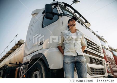 View from below, standing and posing. Truck driver is near the transport outdoors View from below, standing and posing. Truck driver is near the transport outdoors 133336936