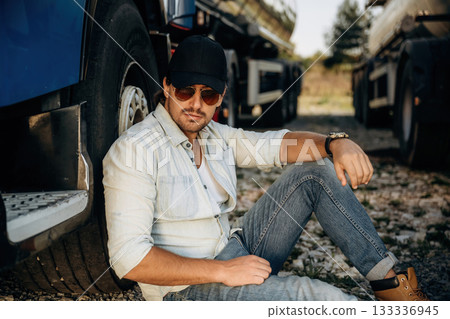 Sitting on the ground. Truck driver is near the transport outdoors 133336945