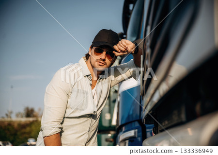 Front view, leaning on the cabin. Truck driver is near the transport outdoors 133336949