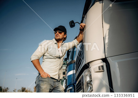 Front view, leaning on the cabin. Truck driver is near the transport outdoors Front view, leaning on the cabin. Truck driver is near the transport outdoors 133336951