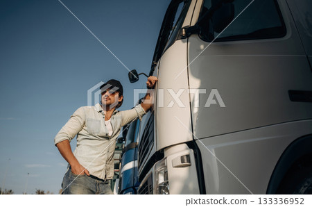 Front view, leaning on the cabin. Truck driver is near the transport outdoors Front view, leaning on the cabin. Truck driver is near the transport outdoors 133336952