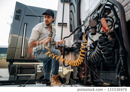 Messing with cables, installation, fix. Truck driver is near the transport outdoors Messing with cables, installation, fix. Truck driver is near the transport outdoors 133336978