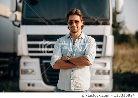 Standing with arms crossed. Truck driver is near the transport outdoors 133336984
