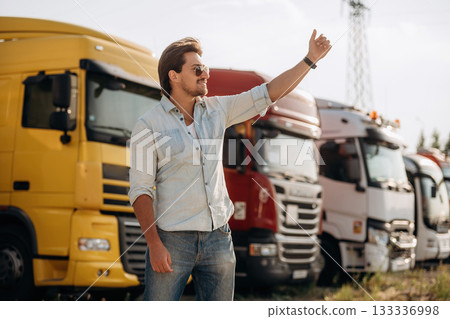 Friendly hand gesture. Truck driver is near the transport outdoors Friendly hand gesture. Truck driver is near the transport outdoors 133336998
