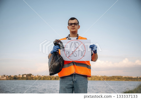 Text 'no plastic' on poster. Man volunteer is against Earth pollution by trash, outdoors 133337133