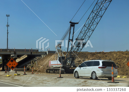 Heavy machinery is actively use crane to lift materials an overpass on highway, affecting traffic flow road access. Heavy machinery is actively use crane to lift materials an overpass on highway, affecting traffic flow road access. 133337268