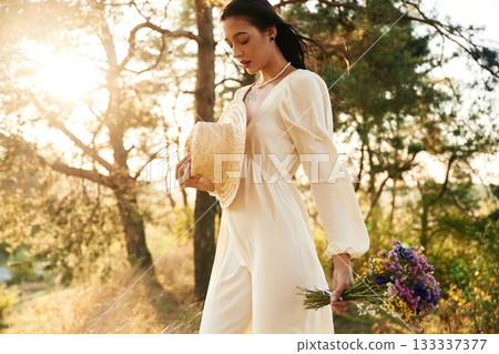 Against sunlight. Woman is outdoors in nature with bouquet of flowers Against sunlight. Woman is outdoors in nature with bouquet of flowers 133337377