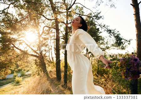 Feeling the freedom. Holding flowers. Woman is outdoors in nature with bouquet of flowers Feeling the freedom. Holding flowers. Woman is outdoors in nature with bouquet of flowers 133337381