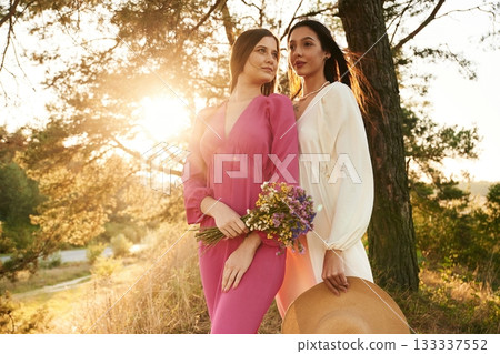 Front view, standing and posing. Lovely lesbian couple are together outdoors in nature Front view, standing and posing. Lovely lesbian couple are together outdoors in nature 133337552