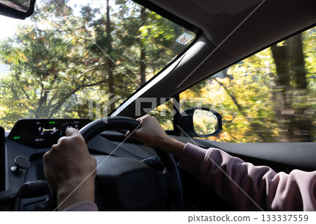 Hands of a man driving on an autumn mountain road Hands of a man driving on an autumn mountain road 133337559