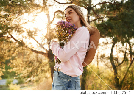 Woman is outdoors in nature with bouquet of flowers 133337565