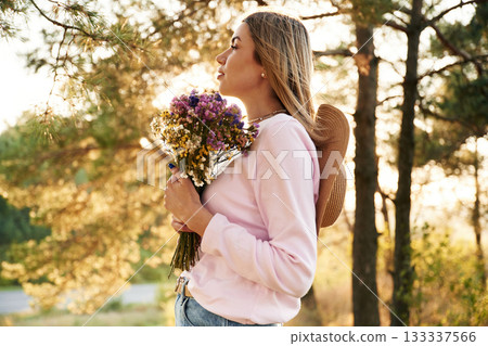 Heartfelt feelings, with bouquet with flowers. Woman is outdoors in nature with bouquet of flowers 133337566